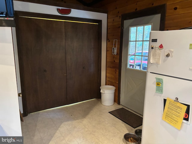 doorway with light floors and wood walls