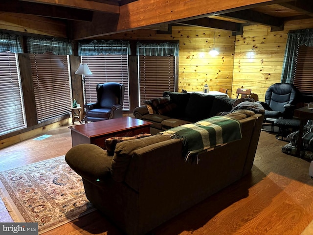 living room with beam ceiling, wooden walls, visible vents, and wood finished floors