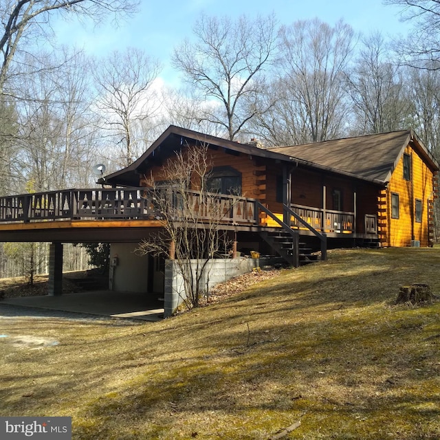 view of home's exterior featuring log siding, an attached carport, and a wooden deck