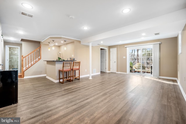 living area with visible vents, stairs, baseboards, and wood finished floors