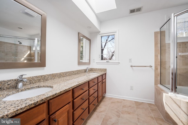 full bathroom featuring visible vents, tiled shower, a skylight, and a sink