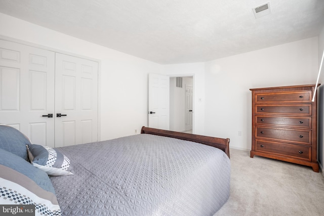 bedroom with a closet, light carpet, and visible vents