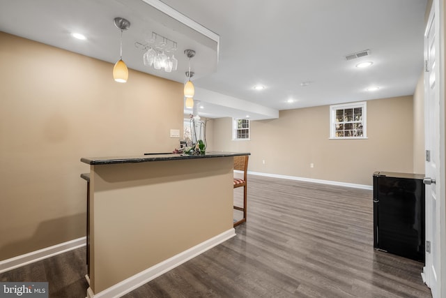 kitchen featuring visible vents, dark wood-type flooring, a kitchen breakfast bar, baseboards, and hanging light fixtures