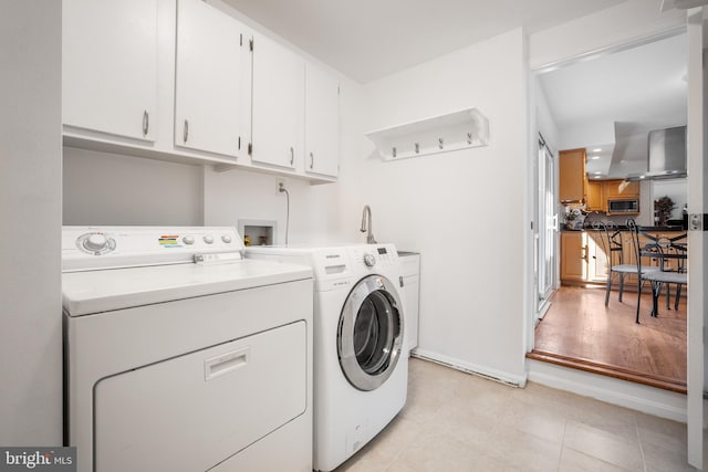 laundry room with washer and dryer, baseboards, cabinet space, and light tile patterned flooring