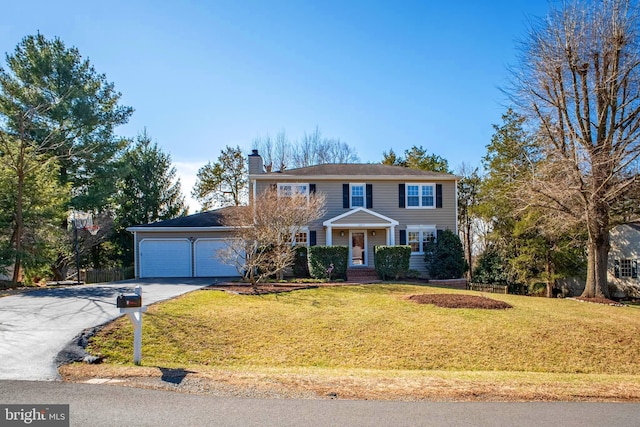 view of front of house featuring driveway, a chimney, a garage, and a front yard