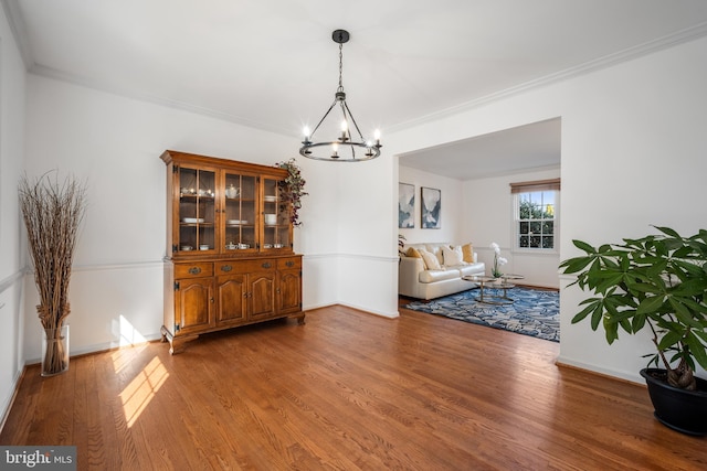 dining area with an inviting chandelier, crown molding, wood finished floors, and baseboards