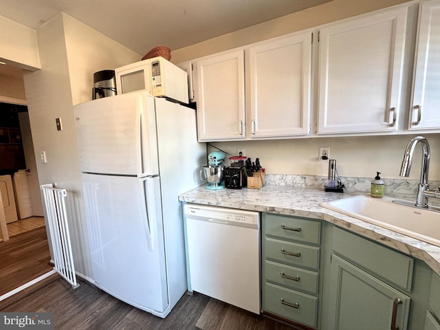 kitchen with dark wood finished floors, light countertops, white appliances, white cabinetry, and a sink