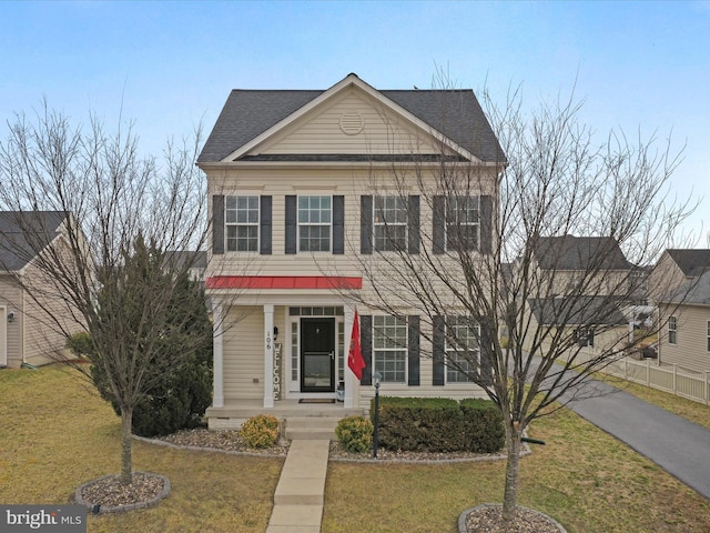 view of front of house featuring fence, a front yard, and a shingled roof