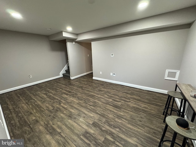 finished below grade area featuring dark wood finished floors, stairs, and baseboards