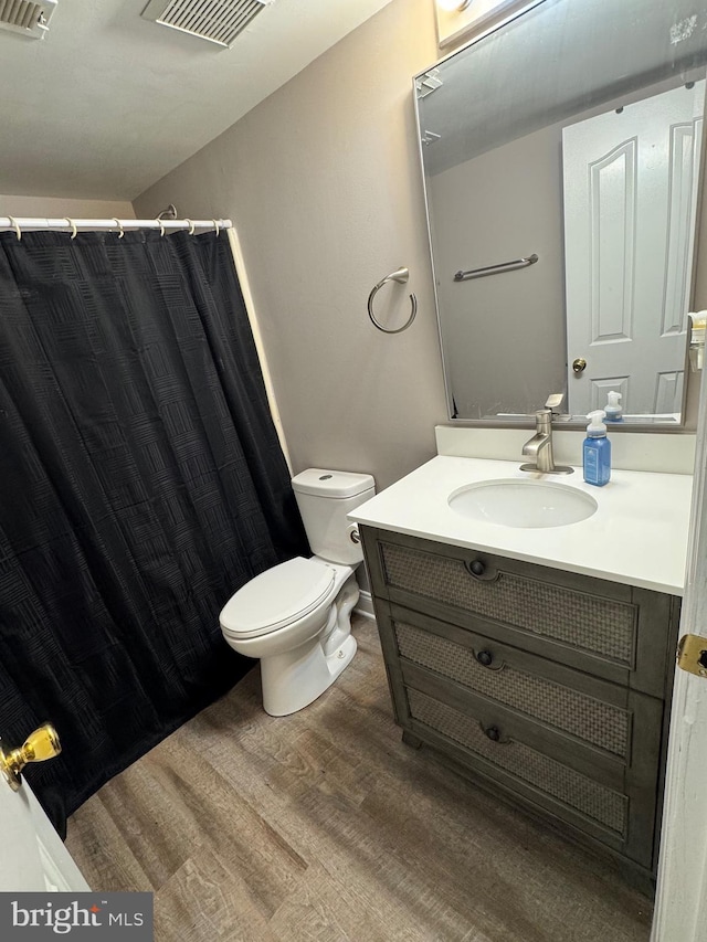 bathroom featuring visible vents, toilet, a shower with curtain, wood finished floors, and vanity