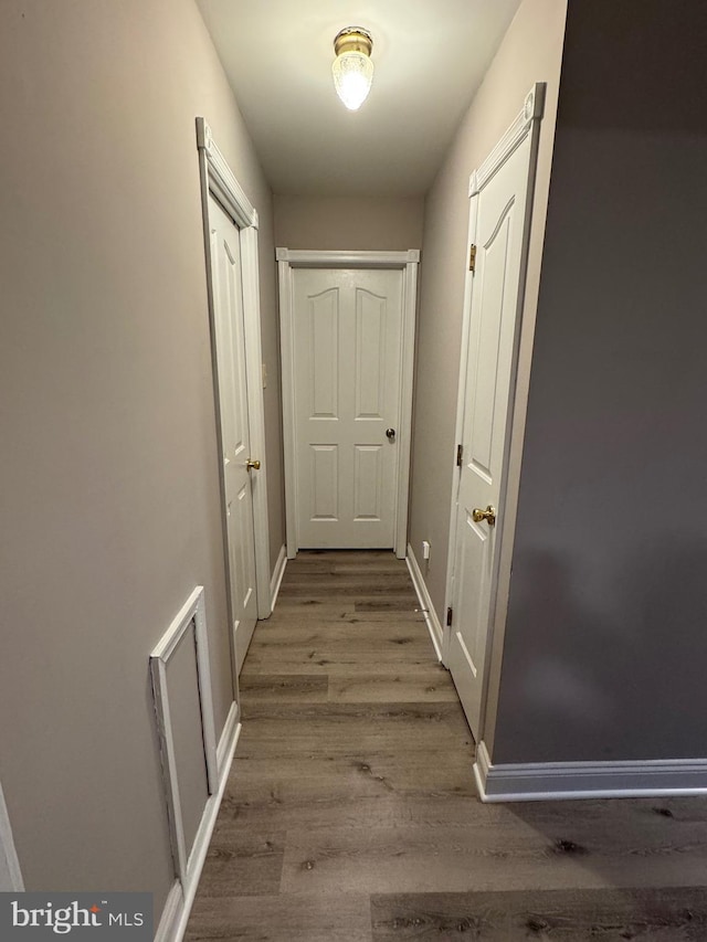 corridor featuring wood finished floors and baseboards