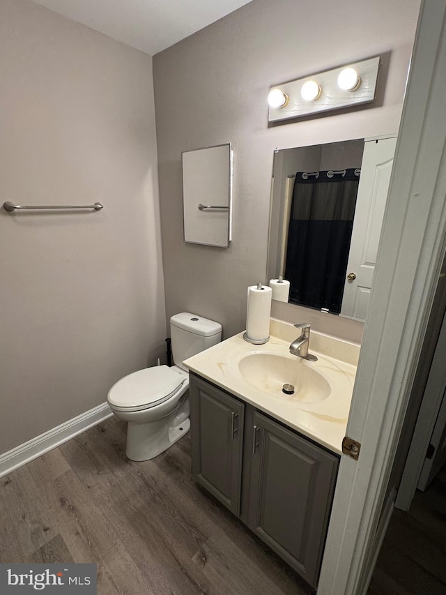 full bathroom featuring vanity, toilet, wood finished floors, and baseboards