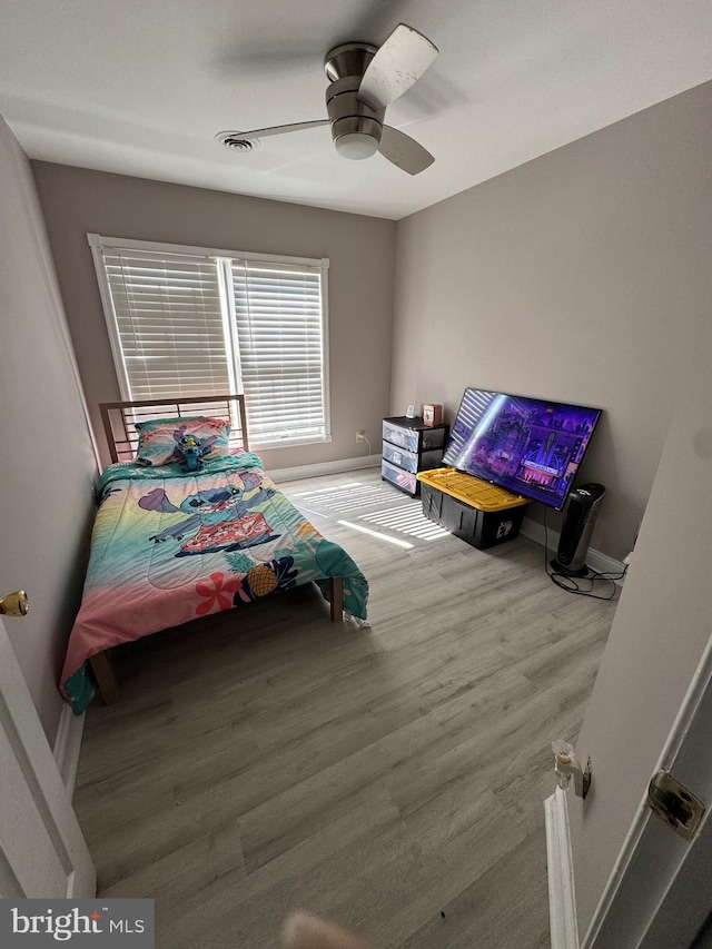 bedroom with a ceiling fan, wood finished floors, and baseboards