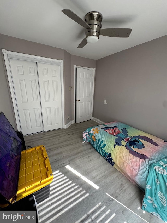 bedroom featuring a closet, a ceiling fan, baseboards, and wood finished floors