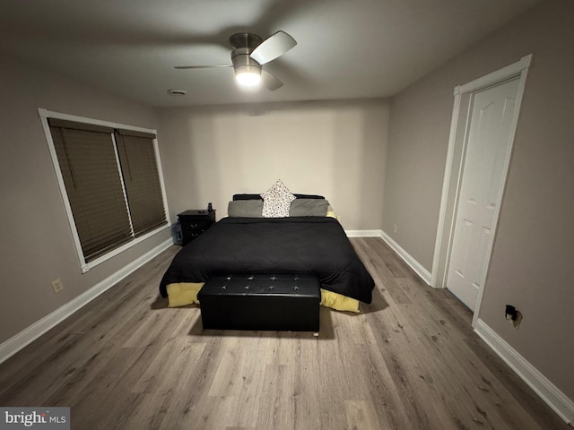 bedroom with a ceiling fan, baseboards, and wood finished floors