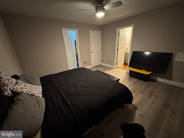 bedroom featuring light wood-style flooring, baseboards, ensuite bathroom, and ceiling fan