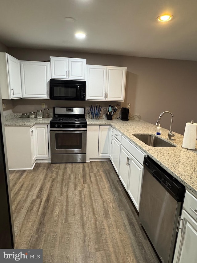 kitchen with a sink, appliances with stainless steel finishes, dark wood-style floors, and white cabinets