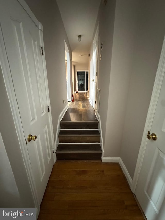 hall featuring visible vents, stairway, baseboards, and wood finished floors