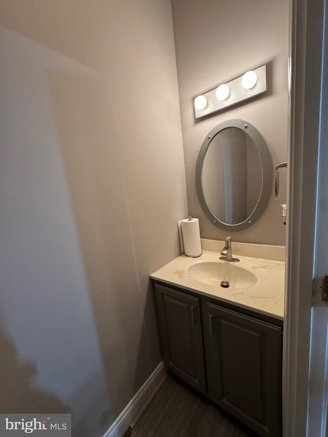 bathroom with baseboards, wood finished floors, and vanity