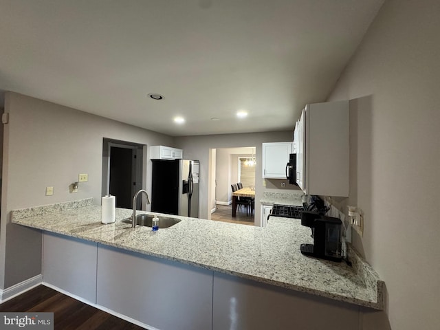 kitchen with a peninsula, stainless steel fridge with ice dispenser, a sink, dark wood-type flooring, and black microwave