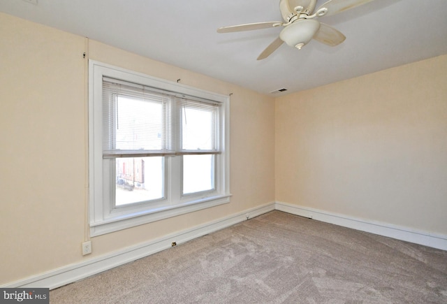 carpeted spare room with visible vents and ceiling fan