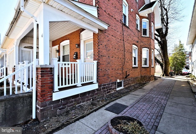 view of side of home with covered porch and brick siding