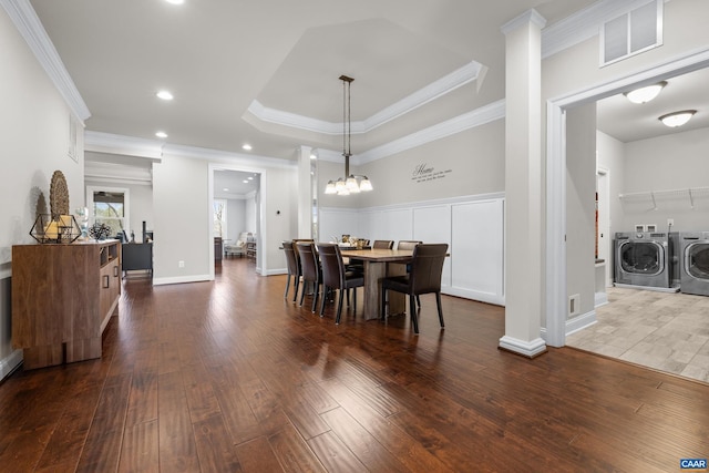 dining room featuring visible vents, ornamental molding, dark wood finished floors, a raised ceiling, and washing machine and clothes dryer