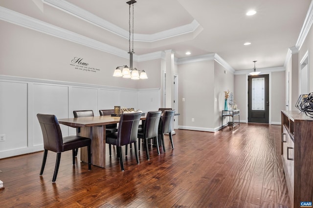 dining space with dark wood-type flooring, ornamental molding, recessed lighting, a decorative wall, and a raised ceiling