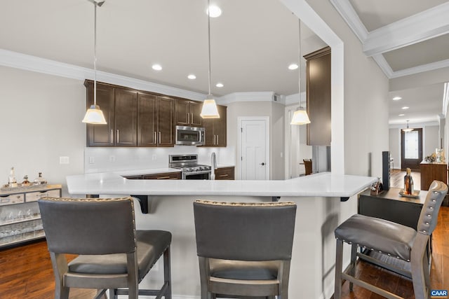 kitchen featuring dark brown cabinets, crown molding, light countertops, appliances with stainless steel finishes, and dark wood-style flooring