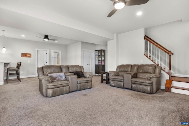 living room featuring carpet, ceiling fan, and stairs