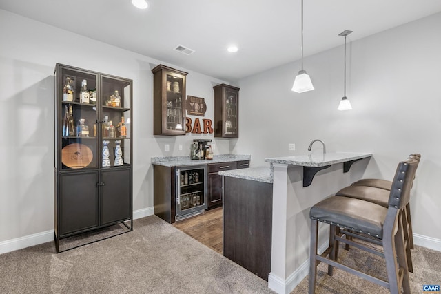 bar with visible vents, beverage cooler, dark carpet, baseboards, and indoor bar