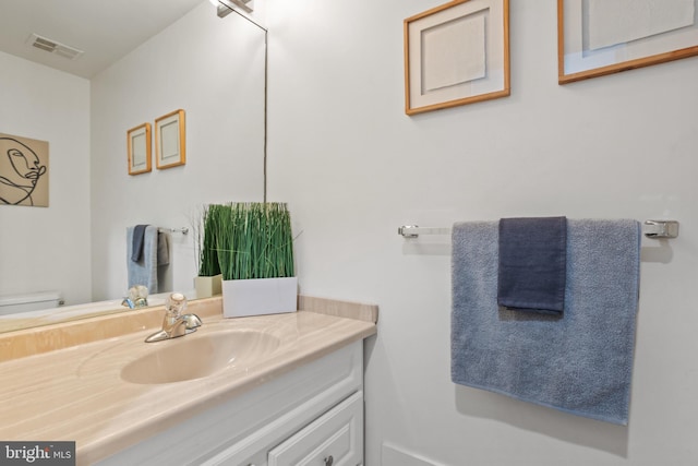 half bath featuring visible vents, toilet, and vanity