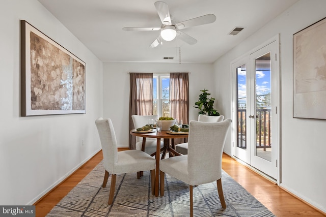 dining room featuring visible vents, light wood-style flooring, french doors, and baseboards