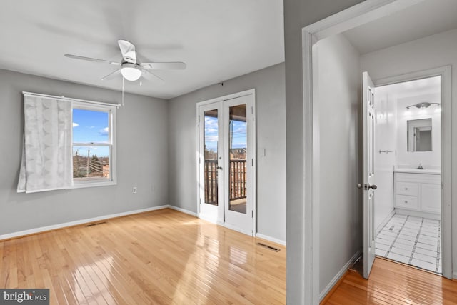 empty room with a ceiling fan, baseboards, visible vents, and wood-type flooring