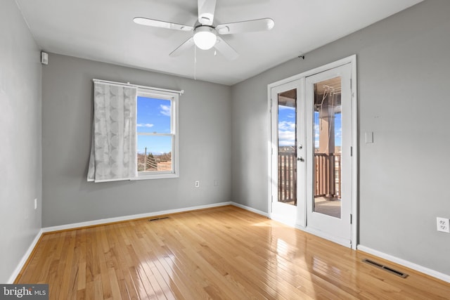 spare room featuring visible vents, baseboards, hardwood / wood-style flooring, and french doors