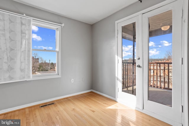 unfurnished room with visible vents, wood-type flooring, and baseboards