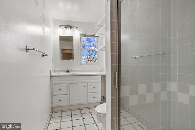 bathroom with tile patterned floors, tiled shower, toilet, and vanity