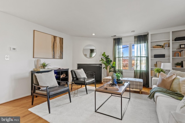 living room featuring a fireplace, light wood-type flooring, and baseboards