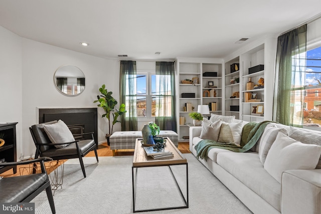 living area with visible vents, a fireplace, and light wood finished floors