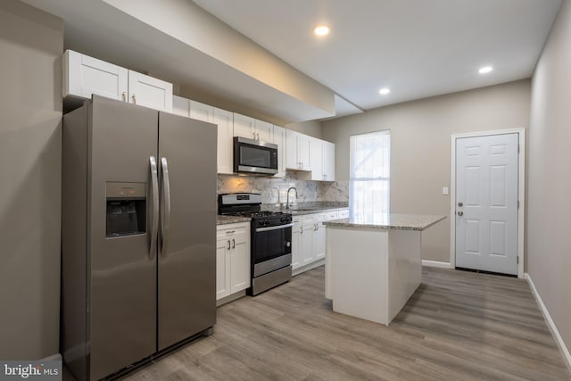 kitchen with tasteful backsplash, white cabinetry, stainless steel appliances, and light stone countertops