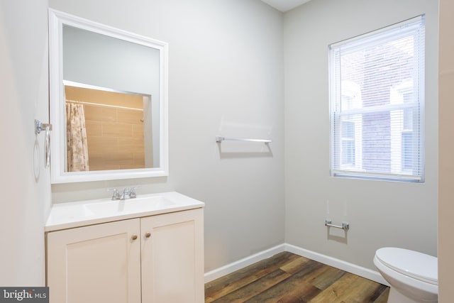 full bathroom featuring vanity, wood finished floors, baseboards, and a wealth of natural light