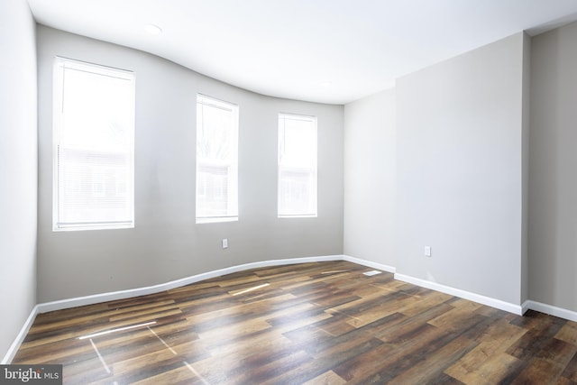 empty room featuring dark wood-style floors and baseboards