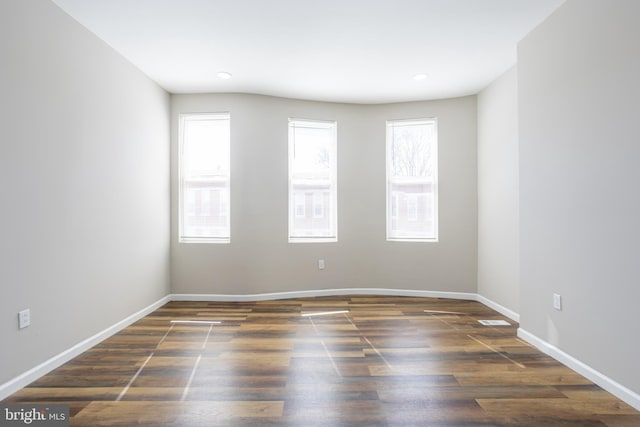 unfurnished room with plenty of natural light, wood finished floors, and baseboards