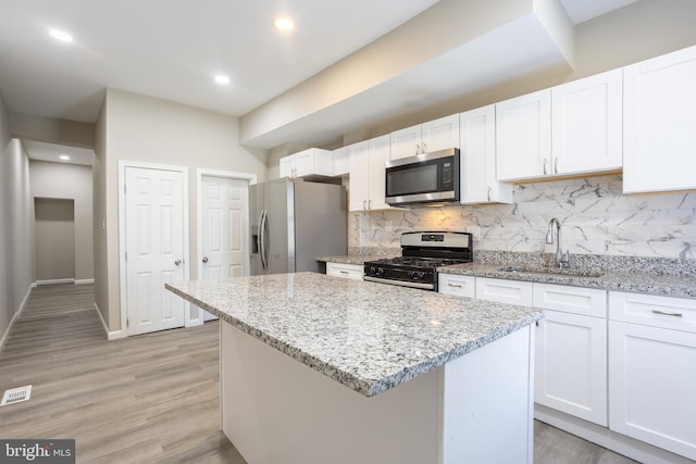 kitchen with tasteful backsplash, a center island, white cabinets, stainless steel appliances, and a sink