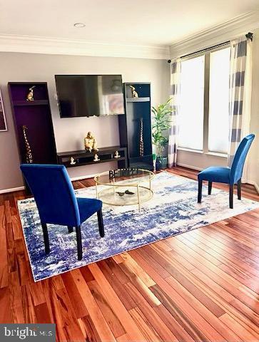 living area featuring wood finished floors and ornamental molding