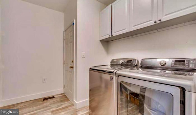 laundry area featuring visible vents, washer and dryer, cabinet space, light wood-style floors, and baseboards