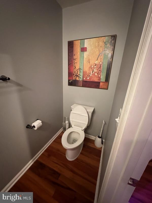 bathroom with toilet, baseboards, and wood finished floors