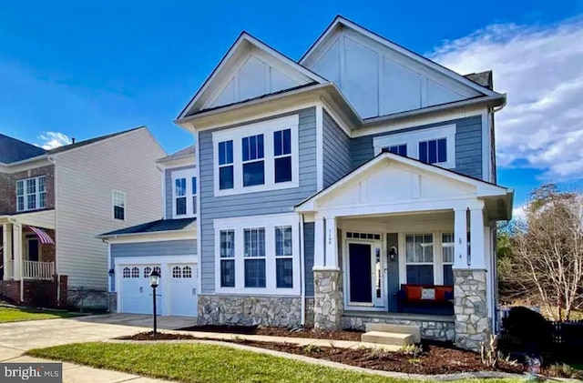 view of front of home with board and batten siding, a porch, concrete driveway, and stone siding