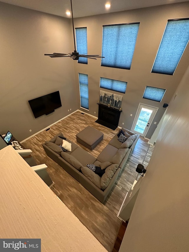 unfurnished living room featuring a fireplace, wood finished floors, baseboards, and a towering ceiling