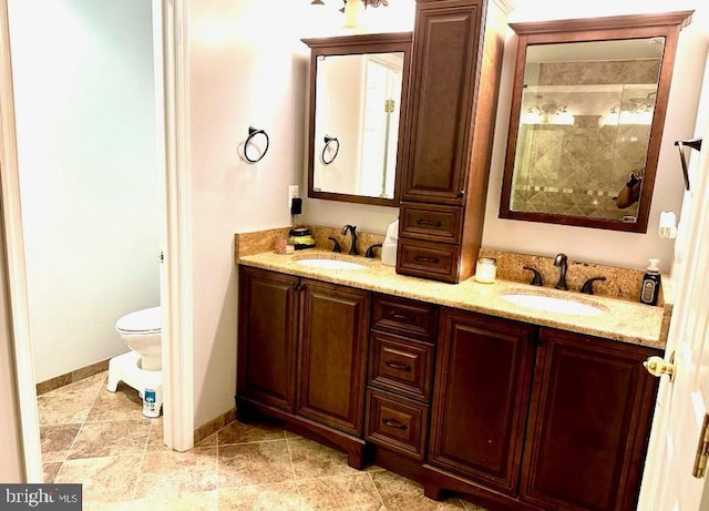 bathroom with a sink, baseboards, toilet, and double vanity